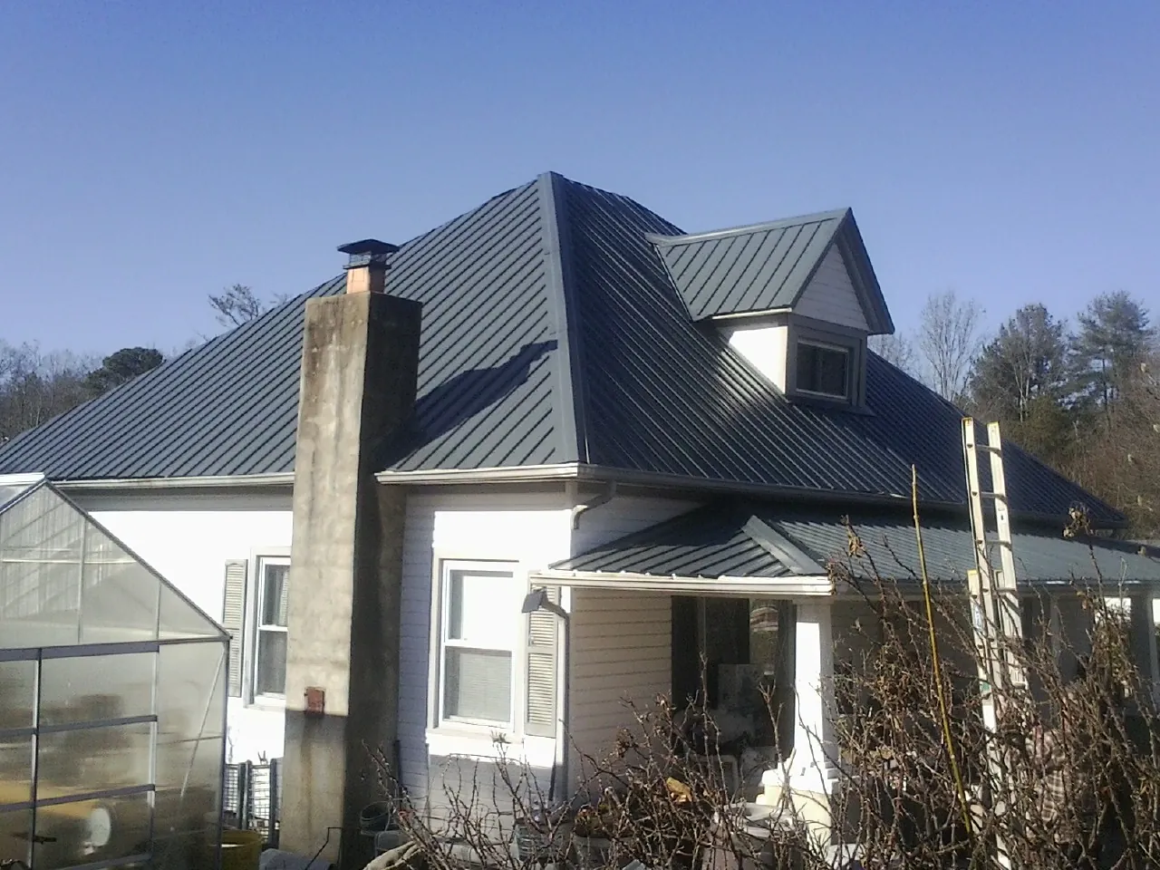 Dark blue standing seam metal roof on a white farmhouse with dormer — Slate & Tile Roof Repair by Roofing Brothers in Wayne
