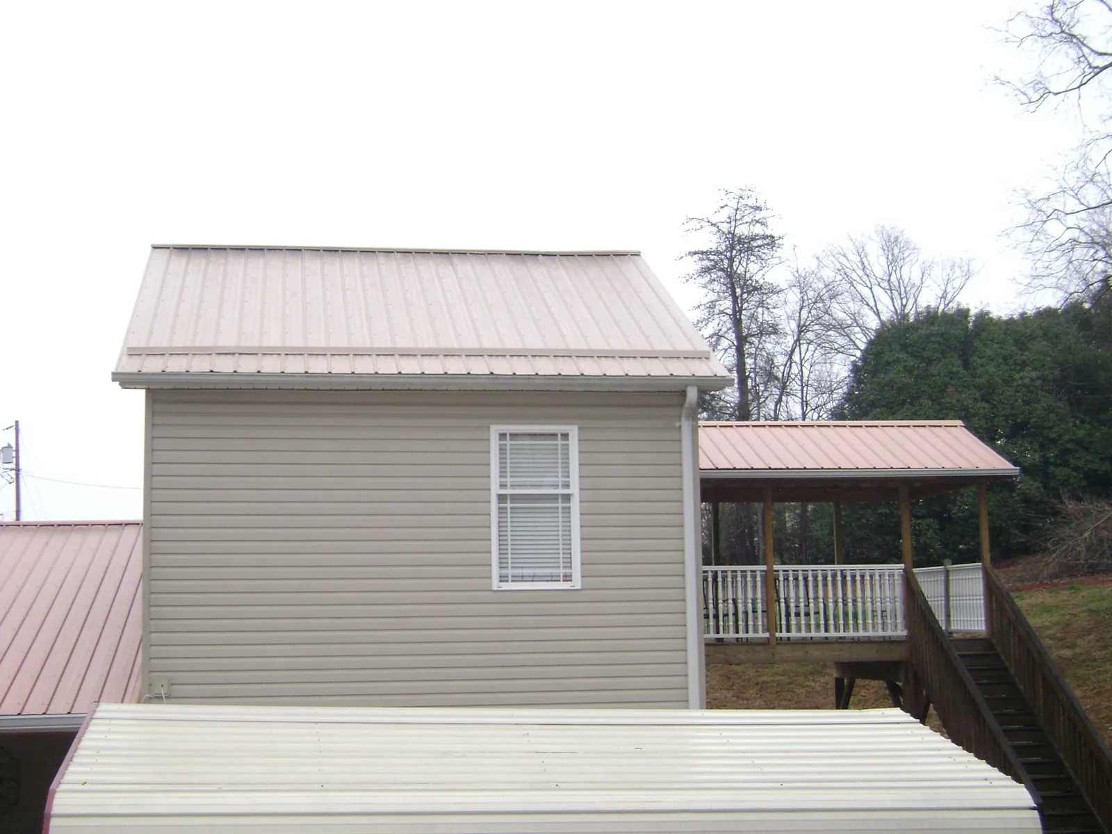 Tan metal roofs on a two story addition and attached porch, from a Roof Replacement job in Wayne